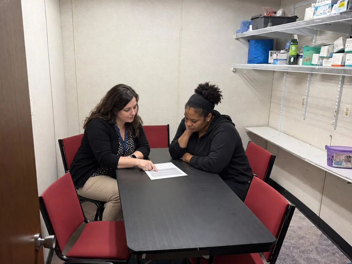 A school advisor reviewing tuition and grant paperwork with an adult student